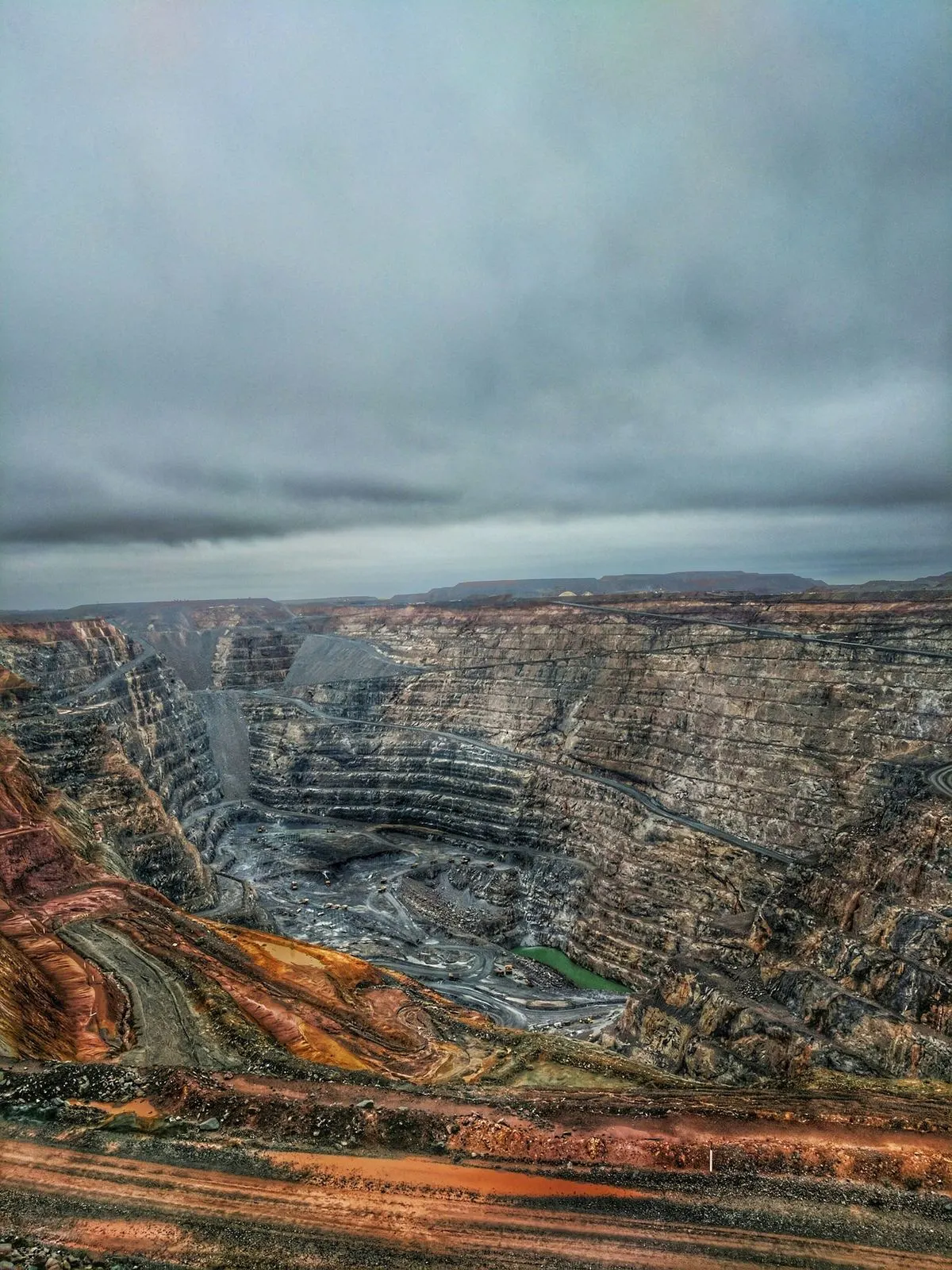 Aerial view of an open-pit mine in operation, showing benches, ramps and haul roads