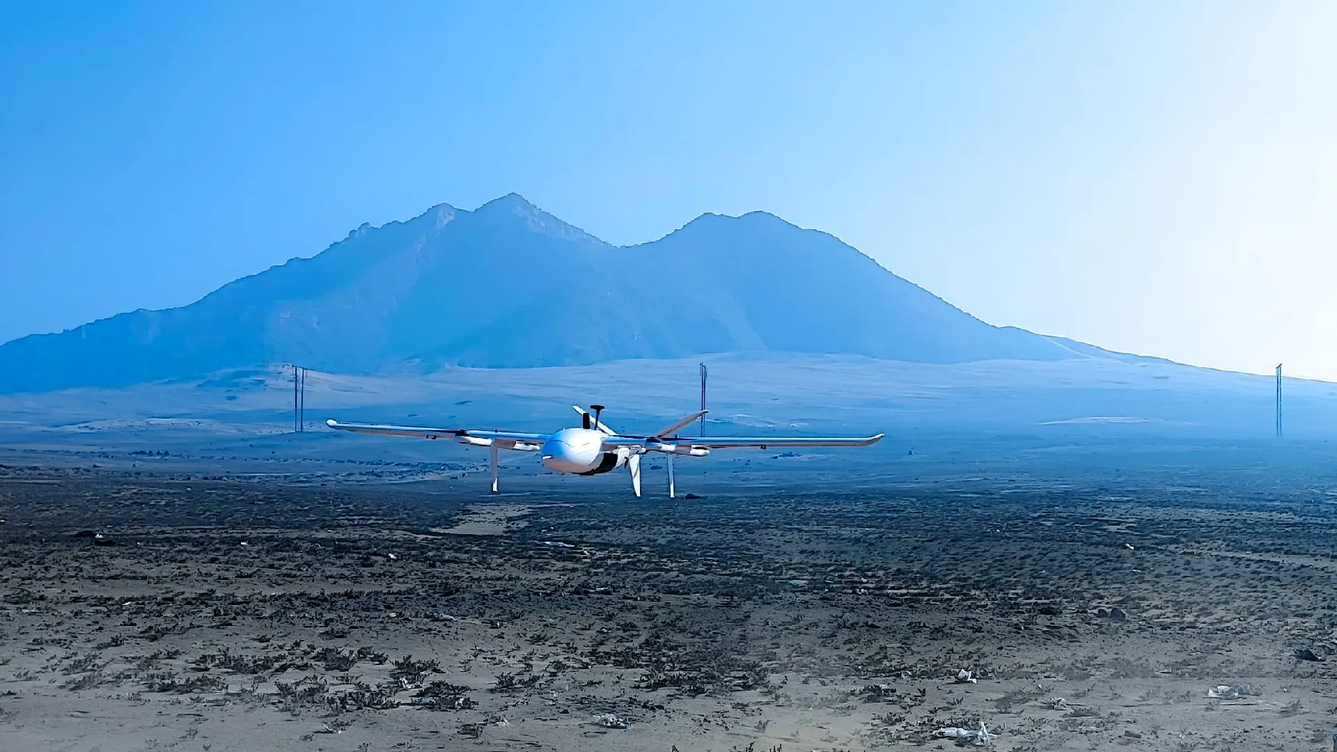 Robotic Air Systems VTOL aircraft in flight over desert terrain with a mountain massif in the background